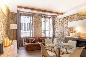Ein gemütliches Wohnzimmer mit Steinwand, Kamin, Sofa, Glastisch und Couchtisch.