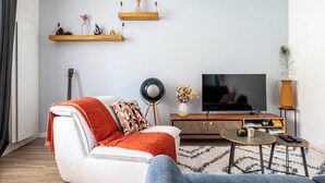 Un soggiorno con divano, tavolino, televisore e chitarra.