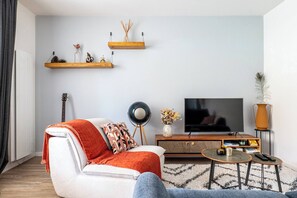 A living room with a sofa, a coffee table, a TV, and a guitar. - The Squirrel Garden - Terrace - Parking - Lake (Annecy)