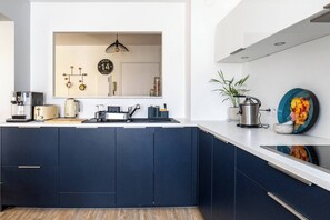 A modern kitchen with dark cabinets, a white countertop, a sink, a stove, and a hanging pendant light. - The Squirrel Garden - Terrace - Parking - Lake (Annecy)