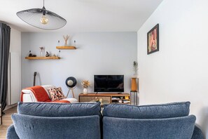 A living room with a sofa, TV, and decorative shelves. - The Squirrel Garden - Terrace - Parking - Lake (Annecy)