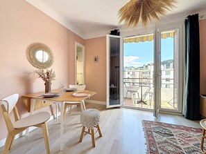 Ein Essbereich mit Tisch, Stühlen und Blick durch eine Glastür auf einen Balkon.