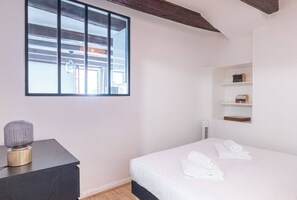 Ein Schlafzimmer mit einem Bett, einem Nachttisch mit Lampe, einem Fenster und eingebauten Regalen.
