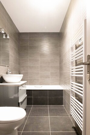 Une salle de bain moderne avec un lavabo, des toilettes et une baignoire.