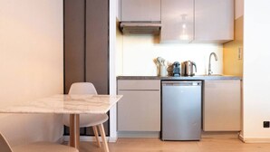 Una cocina compacta con lavavajillas, un lavabo y una estufa. Hay una mesa de comedor con sillas.