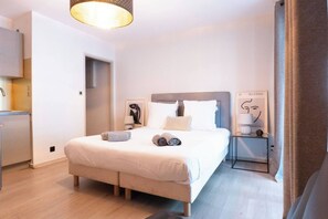A modern hotel room with a bed, bedside tables, and a view of the hallway. - L'Adresse - City - Annecy (Annecy)