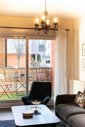 Ein Wohnzimmer mit Sofa, Sessel, Couchtisch und einer Deckenleuchte.