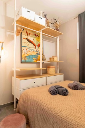 Ein Schlafzimmer mit einem Bett, einer weißen Kommode, einem Regal mit Dekoration und einem Vogelgemälde.