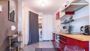 Una cocina compacta con encimera roja, estufa y lavamanos.