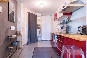 Eine kleine Küche mit roter Arbeitsplatte, einem Herd und einem Spülbecken.