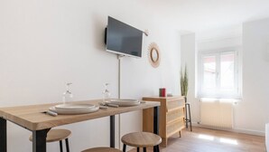 Eine moderne Küche mit Flachbildfernseher, Holztisch, Barhocker und Heizkörper.
