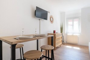 Eine moderne Küche mit Flachbildfernseher, Holztisch, Barhocker und Heizkörper.