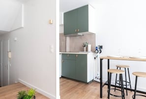 Eine moderne Küche mit grünen Schränken, einer Holzarbeitsplatte und zwei Barhocker.