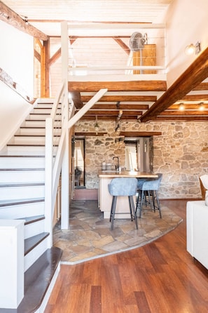 A spacious loft with a stone wall, a kitchen area with bar stools, and a wooden staircase. - Under the Annecy sky - Pedestrian street - City center - Balcony (Annecy)