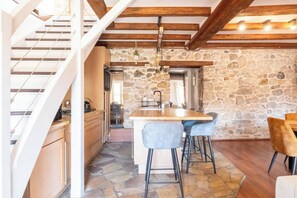 A kitchen with a stone wall, wooden beams, a central island, and bar stools. - Under the Annecy sky - Pedestrian street - City center - Balcony (Annecy)