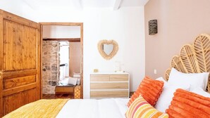 Une chambre à coucher comprenant un lit, une commode, un miroir et une porte donnant sur une salle de bain.