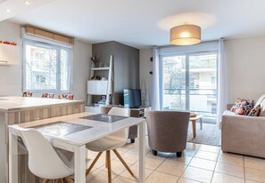 Ein modernes Wohnzimmer mit Essbereich, Fernseher und Sofa.