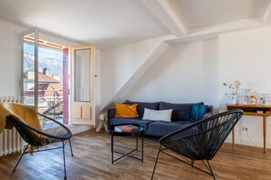 A modern living room with a sofa, two chairs, a small table, and a view through an open door. - LA HAUT - Center annecy- Balcony view lake (Annecy)