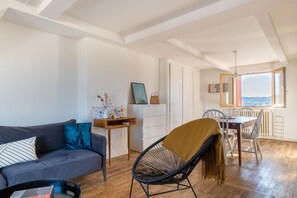 A modern living room with a sofa, a chair, a dining table, and a view through a window. - LA HAUT - Center annecy- Balcony view lake (Annecy)