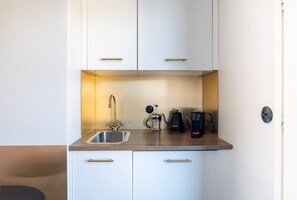 Eine kompakte Küche mit Spüle aus Edelstahl, einer Kaffeemaschine und einem Wasserkocher.