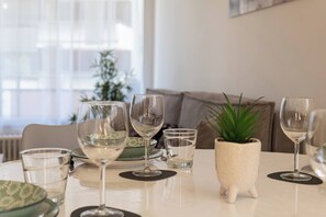 Ein Esstisch mit Weingläsern, einem Wasserglas und einer Topfpflanze.