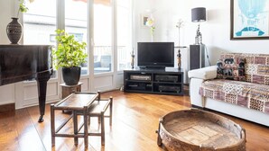 A living room with a piano, television, sofa, and a decorative wooden table. - At the gates of the old town - 2 bedrooms - Garage - Terrace (Annecy)