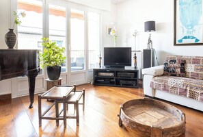 A living room with a piano, television, sofa, and a decorative wooden table. - At the gates of the old town - 2 bedrooms - Garage - Terrace (Annecy)