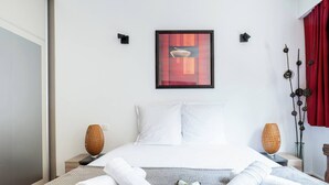 A hotel room with a bed, two bedside tables, a framed picture, and a red curtain. - At the gates of the old town - 2 bedrooms - Garage - Terrace (Annecy)