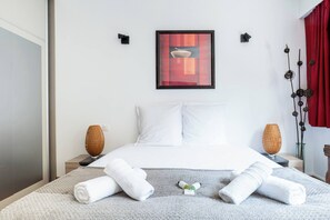 A hotel room with a bed, two bedside tables, a framed picture, and a red curtain. - At the gates of the old town - 2 bedrooms - Garage - Terrace (Annecy)