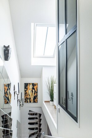Ein modernes Interieur mit einem Oberlicht, einer Treppe und Kunstwerken an den Wänden.