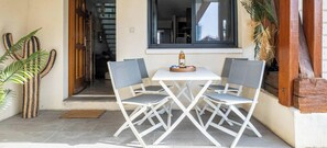 Eine Terrasse mit einem weißen Tisch, vier Stühlen, einer Getränkeflasche und einer Kakteendekoration.