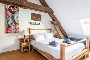 Ein Zimmer mit einem Holzbett, einem Nachttisch, einer Lampe, einem Gemälde und einem dekorativen Regal.