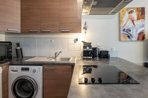 Eine moderne Küche mit einer Bosch Waschmaschine, einem Spülbecken, einer Kaffeemaschine und einem Bild an der Wand.