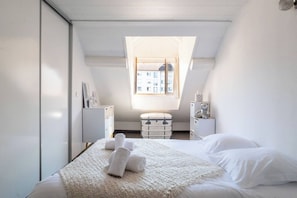 Ein Schlafzimmer mit Bett, Fenster, Kommode und Nachttisch.