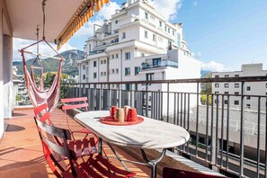 Ein Balkon mit Tisch, Stühlen und einer Hängematte.