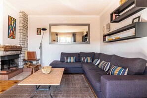 Ein Wohnzimmer mit Ecksofa, Kamin, Spiegel und Regalen mit Büchern und Dekoration.