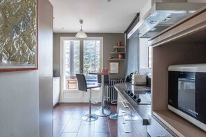 Eine moderne Küche mit integriertem Mikrowellenherd, einem Essbereich mit Tisch und Stühlen sowie einem großen Fenster, das für natürliches Licht sorgt.
