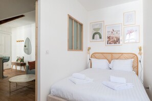Ein Schlafzimmer mit einem Bett, einem Sessel, einem Schreibtisch, einem Spiegel und gerahmten Bildern an der Wand.