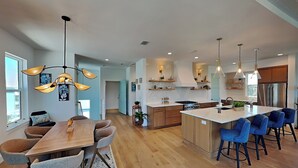 A modern kitchen with a central island, wooden flooring, and pendant lighting. - Ocean Escape (St. Augustine)