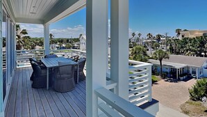 A covered outdoor area with a table and chairs, a view of the surrounding area, and a clear sky. - Ocean Escape (St. Augustine)