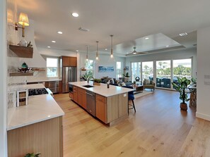 Una cocina moderna con una isla grande, armarios de madera y un comedor con vistas.