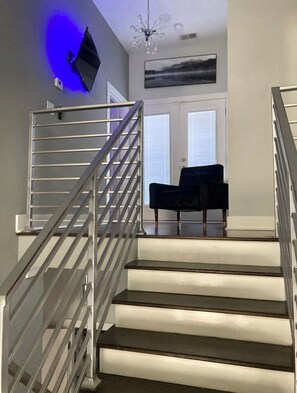 Eine Treppe mit Metallgeländer führt zu einer Empore, auf der ein schwarzer Stuhl steht.