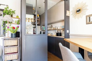 Eine Küche mit einem Holztisch, Korbwannen, einer Lampe und einem Spiegel.