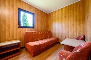 Una habitación pequeña con detalles de madera, un banco integrado, una mesita y una ventana con vistas a la vegetación.