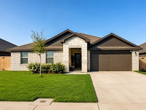 A residential house with a stone facade, a front garage, and a well-maintained lawn.
