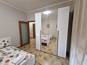 A bedroom with a bed, a wardrobe, and a mirror.