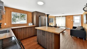 Une cuisine moderne avec des meubles en bois, un îlot central et un coin repas agrémenté d’un canapé.