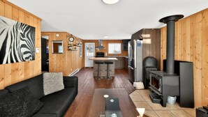 Un intérieur de chalet chaleureux comprenant un salon, une cuisine et un poêle à bois.