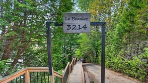 Un pont en bois, sur lequel est apposée une plaque indiquant « Le Beaulac 3214 », dans une zone boisée.