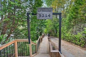Uma ponte de madeira com uma placa indicando 'Le Beaulac 3214' em uma área arborizada.